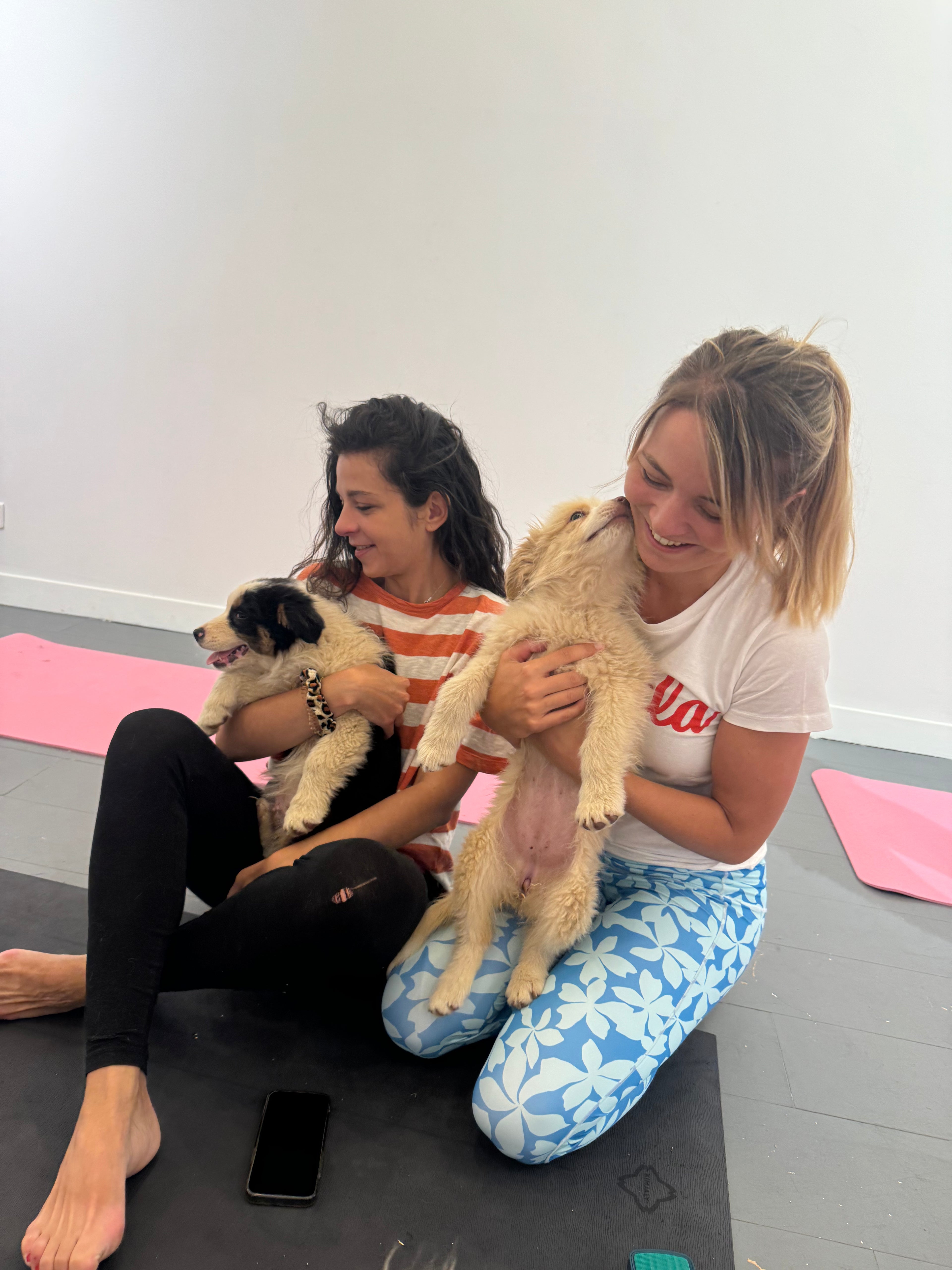 Dos participantes de Puppy Yoga Mx con cachorros